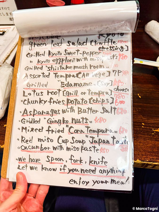 Un menu scritto a mano su un foglio plastificato che elenca piatti presso il ristorante Gion Yuki a Kyoto.