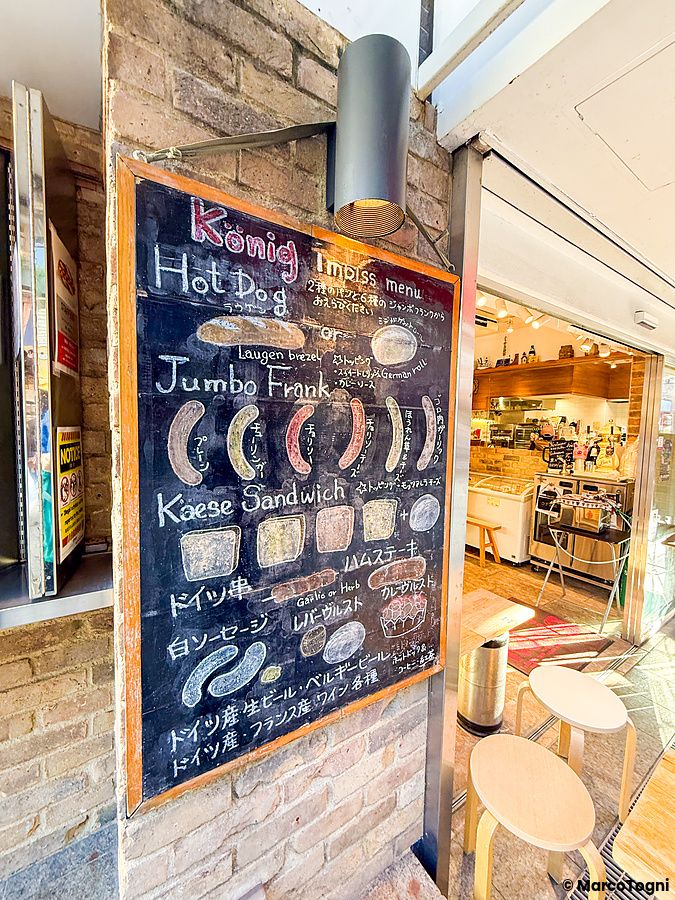 Una lavagna con menu illustrato a gesso per il ristorante König a Kichijoji appesa su una parete di mattoni.
