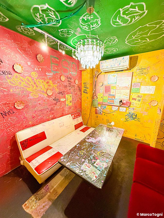 Interni colorati del ristorante vegano e gluten free OKO a Osaka, con pareti piene di scritte lasciate dai clienti.