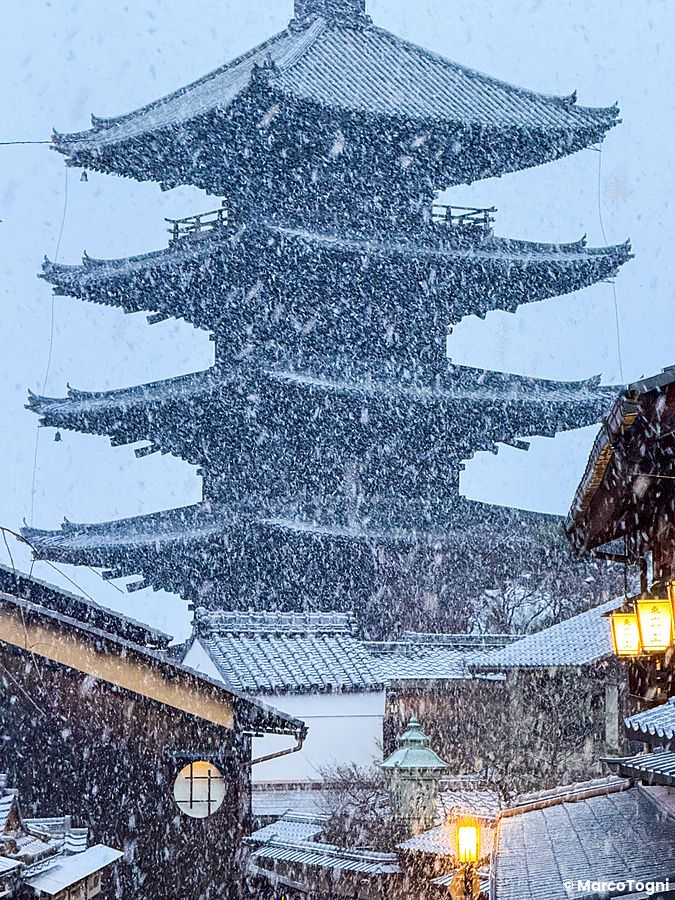 La Pagoda Yasaka di Kyoto si staglia tra una fitta nevicata invernale sopra i tetti degli edifici tradizionali in legno.