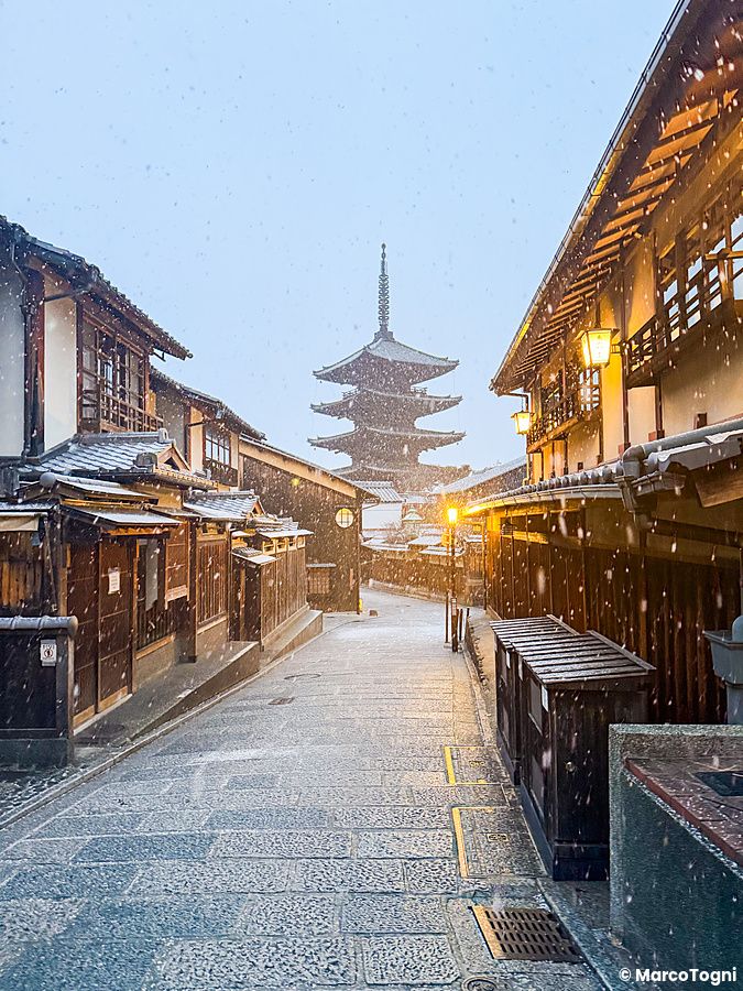 La Pagoda Yasaka a Kyoto si staglia in fondo a una via in salita durante una nevicata invernale.