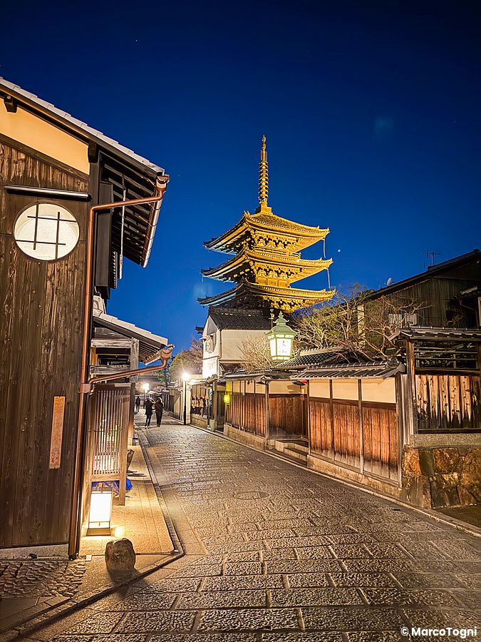 La pagoda Yasaka a Kyoto si erge in un vicolo lastricato illuminato durante l'ora blu con una persona in lontananza.