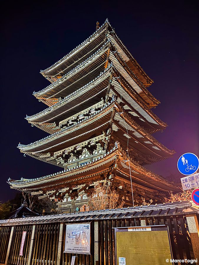 La pagoda Yasaka si erge illuminata di notte nel quartiere Higashiyama a Kyoto, circondata da mura tradizionali.