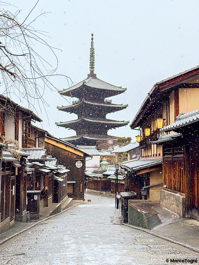 Veduta della Pagoda Yasaka innevata a Kyoto con le tipiche case in legno che fiancheggiano la strada in salita.
