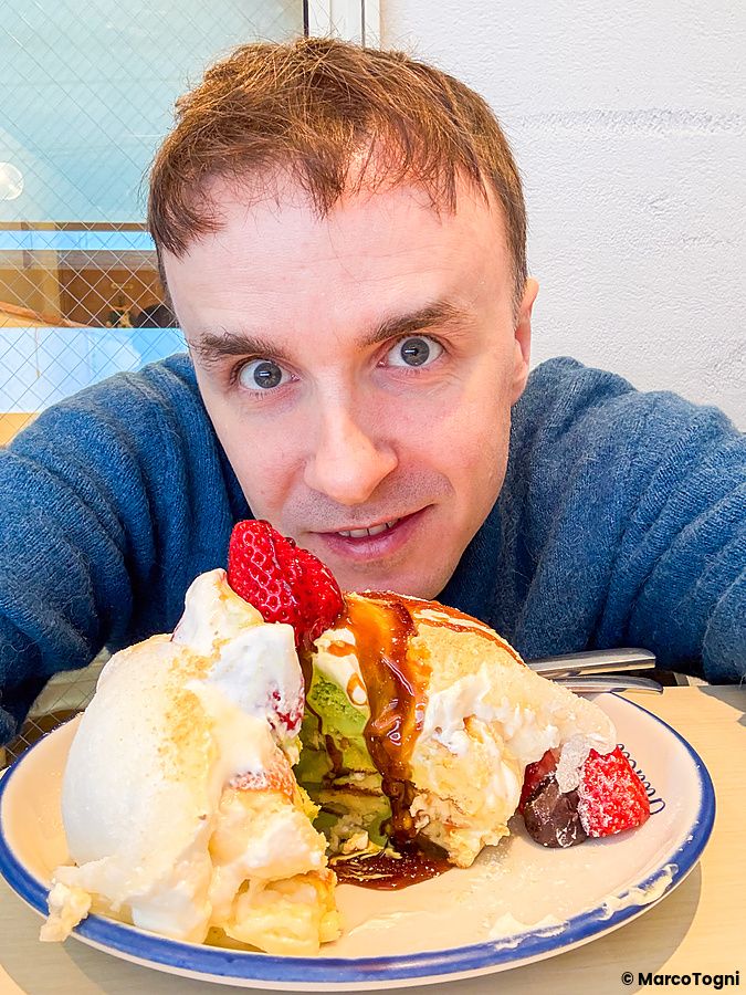 Marco Togni guarda verso l'obiettivo vicino a un piatto di pancake con mochi e fragole presso il locale Chaka a Tokyo.