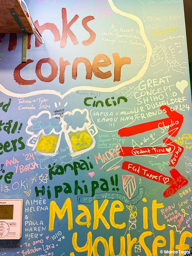 Parete azzurra del ristorante OKO a Osaka coperta di scritte colorate e dediche lasciate dai clienti.