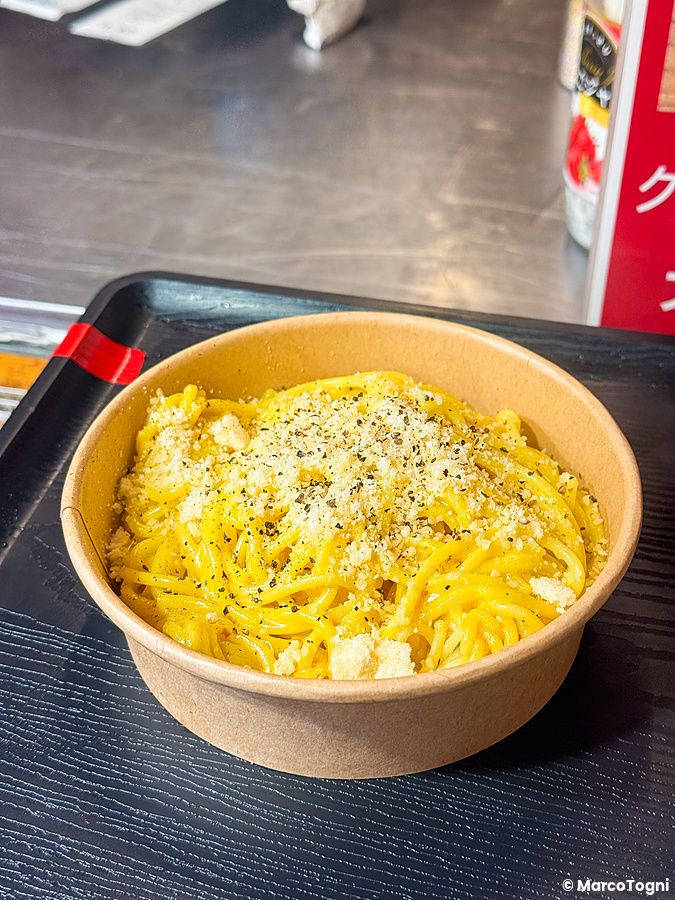 Una porzione di pasta con formaggio e pepe in una ciotola di carta al Yokohama Red Brick Christmas Market.