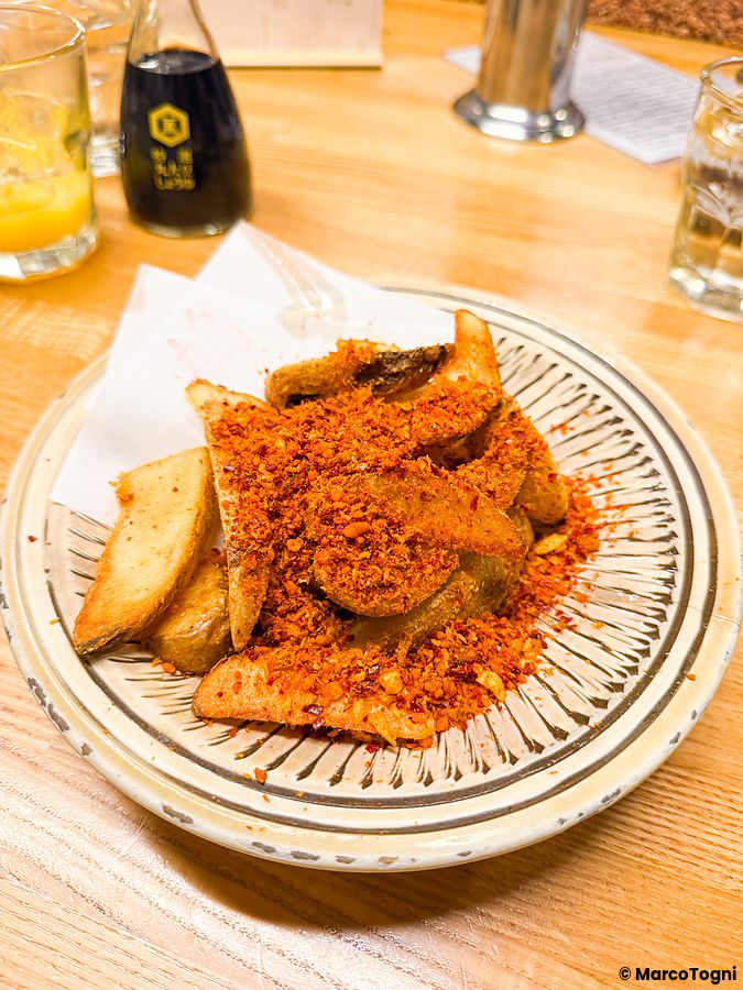 Patatine fritte a spicchi con condimento speziato servite in un piatto di ceramica decorato al ristorante Hatonoyu.