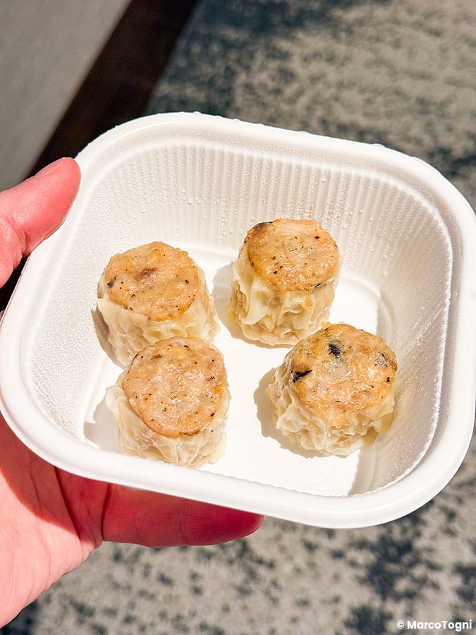 Ravioli cinesi con carne, d'asporto a Wangfujing, tenuti in mano all'interno di una vaschetta bianca.