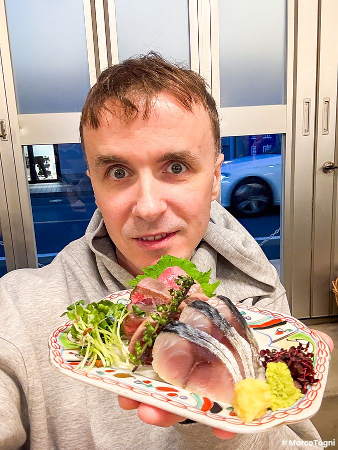Marco Togni mostra un piatto di sashimi con wasabi all'interno dell'izakaya Hatonoyu a Tokyo.