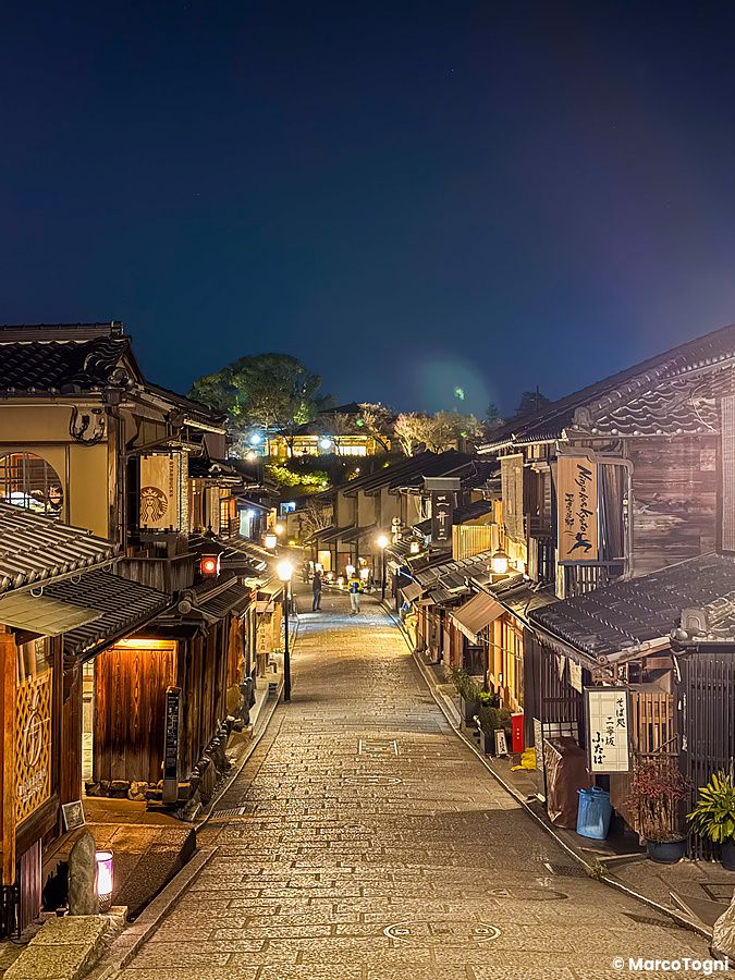 Veduta notturna della storica strada Ninenzaka a Kyoto con i suoi caratteristici edifici in legno illuminati.