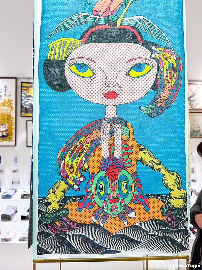 Un tenugui a Eirakuya con un'illustrazione colorata che mostra una persona stilizzata su sfondo blu.