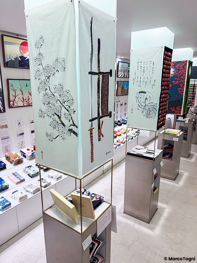 Interno del negozio Eirakuya a Kyoto con espositori verticali che mostrano tenugui decorati con stampe tradizionali.