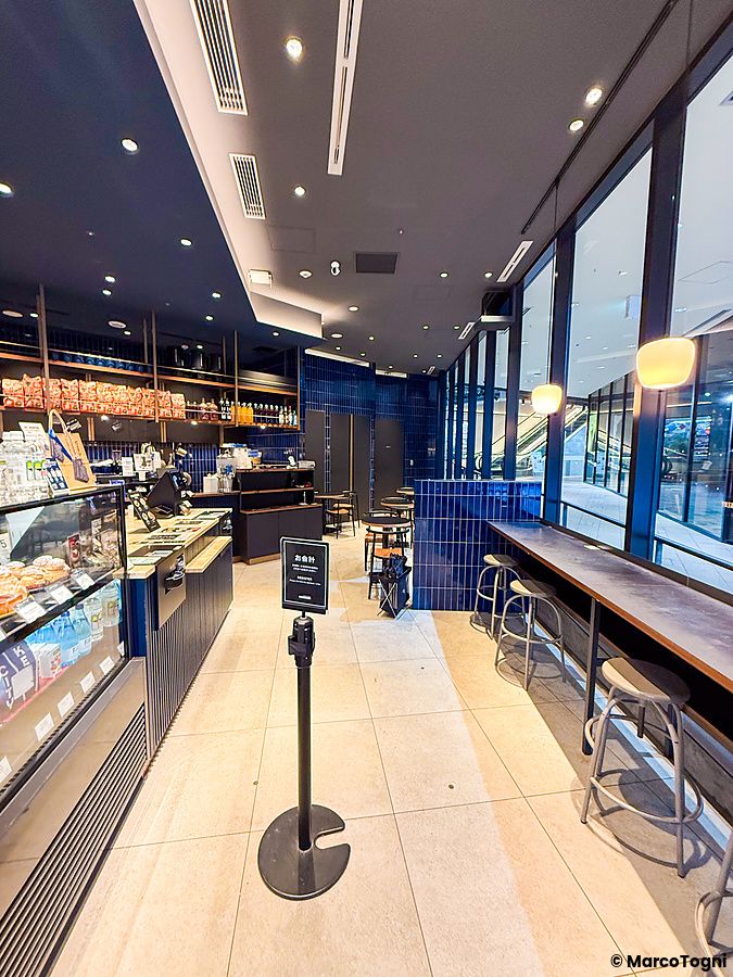 L'interno di The City Bakery a Shibuya, con un bancone, vetrine espositive e sedute lungo una parete vetrata.