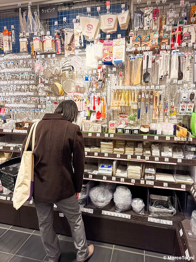 Una persona osserva utensili da cucina esposti sugli scaffali nel negozio Tomizawa Shoten a Machida.