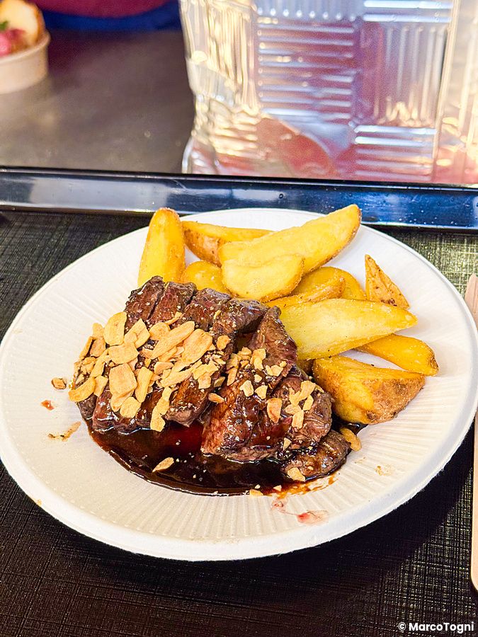 Un piatto con carne a fette e patate a spicchio servito al Yokohama Red Brick Christmas Market.