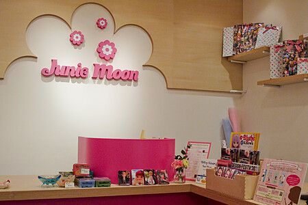 Interno del negozio Junie Moon con esposizione di prodotti e logo sulla parete.
