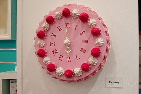 Orologio decorativo a tema torta con cornice rosa e decorazioni al negozio Junie Moon.
