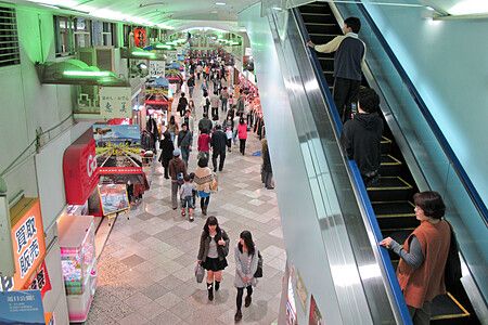 Centro commerciale Mandarake affollato con scala mobile e persone che passeggiano