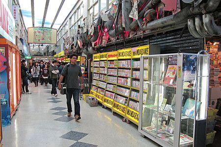 Corridoio di Nakano Broadway a Tokyo con scaffali di Mandarake e persone