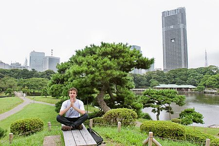 Persona medita su una panchina in un parco con grattacieli sullo sfondo