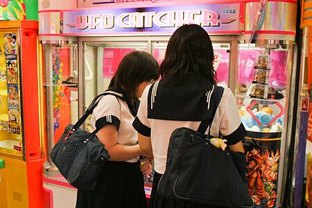 Due ragazze in uniforme scolastica giocano a un ufo catcher in giappone