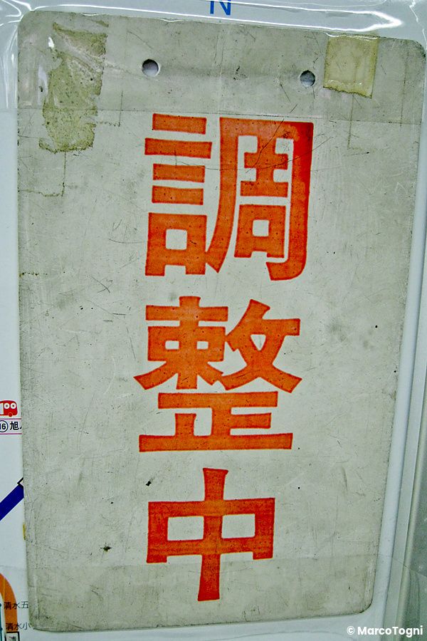 Cartello con kanji rossi su sfondo bianco appeso in Giappone.