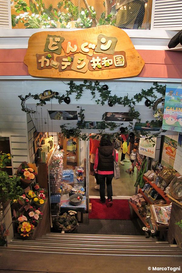 Ingresso del Negozio dello Studio Ghibli in Giappone, con scalinata che scende verso scaffali pieni di gadget.