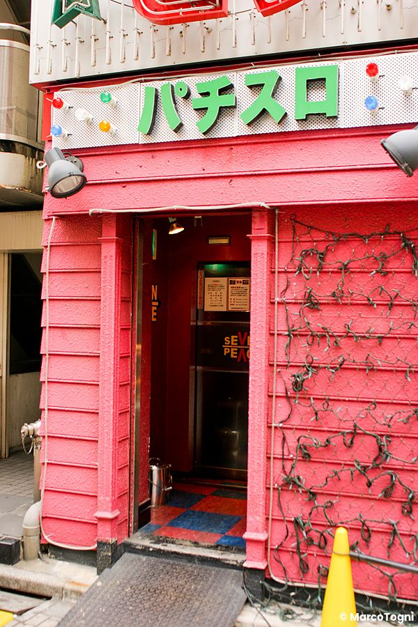 Ingresso di un pachinko in giappone con pareti rosa e insegne al neon.