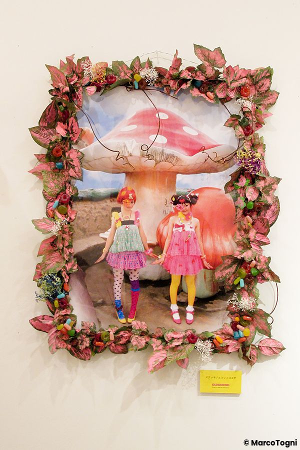 Due bambole Blythe in una cornice decorata con foglie rosa.