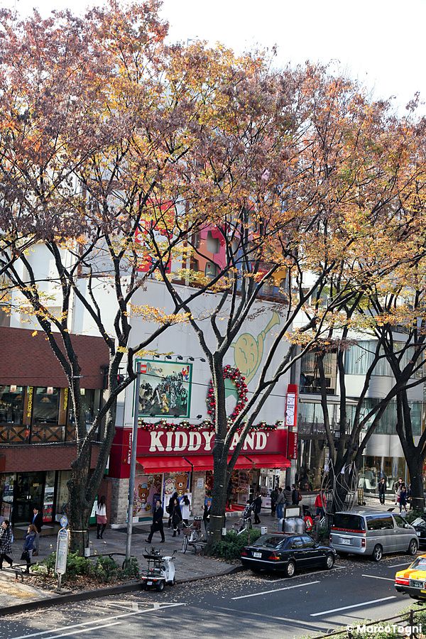 Vista esterna dell'edificio Kiddyland ad Harajuku con persone e auto di passaggio.