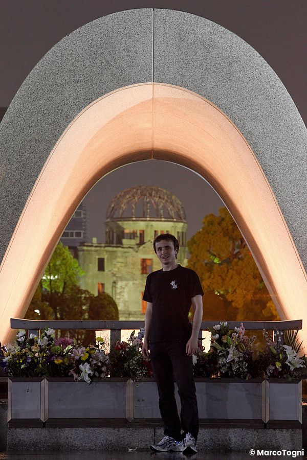 Una persona davanti al cenotafio con la cupola di Hiroshima sullo sfondo.