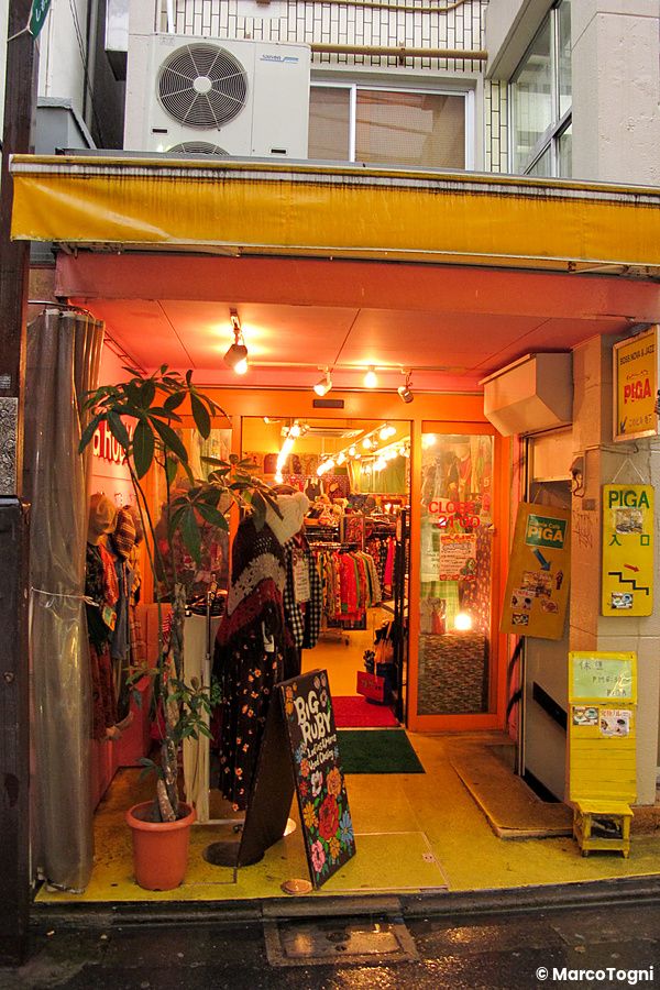 Vetrina di un negozio vintage a Shimokitazawa con abiti colorati e luci calde.