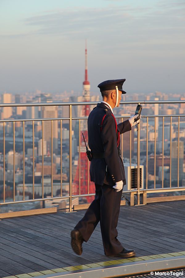 Persona in uniforme sul tetto di Roppongi Hills con vista su Tokyo Tower