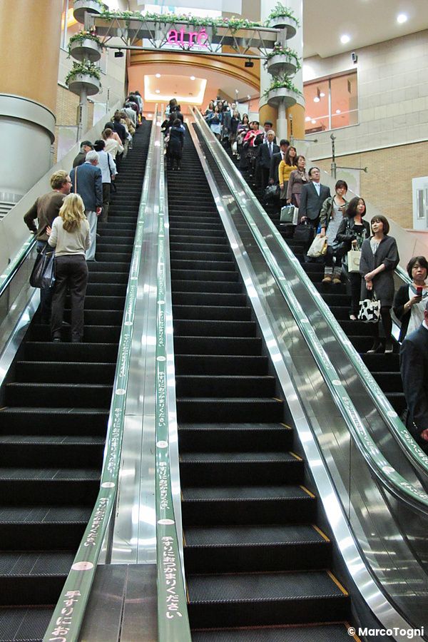 Una lunga scala mobile giappone in Giappone trasporta diverse persone su più livelli all'interno di un edificio.