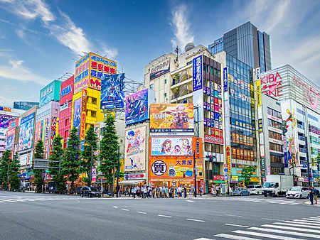 Intersezione trafficata ad Akihabara, Tokyo, con edifici e cartelloni colorati.