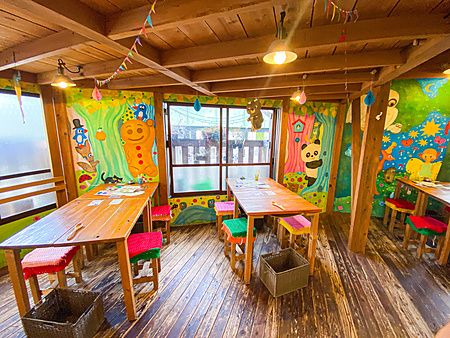 L'interno del ristorante Hattifnatt a Kichijoji con tavoli in legno, pareti colorate dipinte e sedute lavorate a maglia.