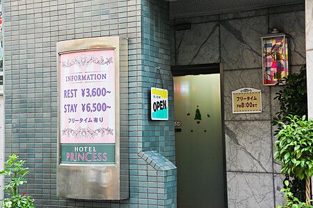Entrata di un love hotel in Giappone con prezzi indicati su un'insegna.