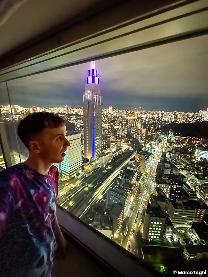 Persona che guarda Tokyo di notte dalla finestra dell'Hotel Century Southern Tower.