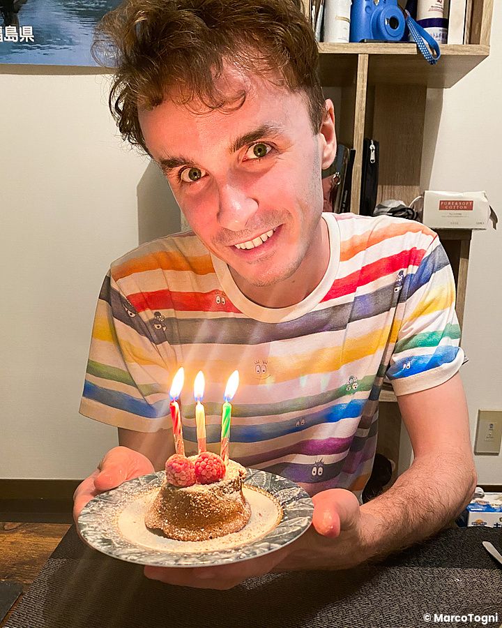 Marco Togni con torta di compleanno e candeline accese in un ambiente interno