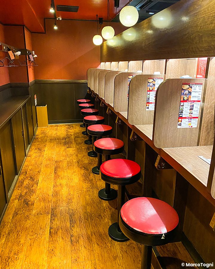 L'interno a Ichiran presenta una fila di sgabelli rossi e singoli cubicoli in legno per mangiare ramen.