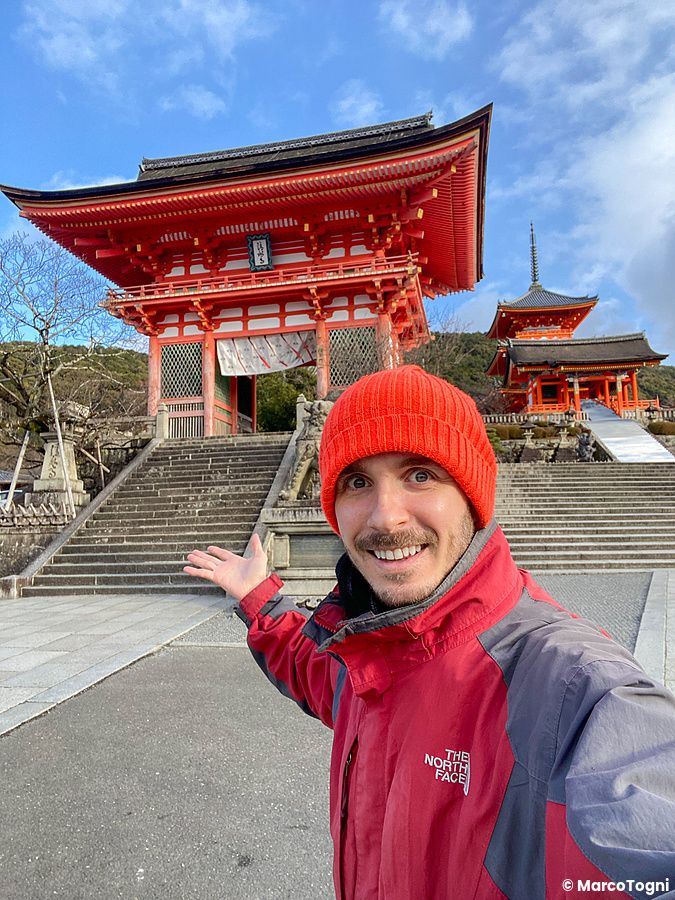 Marco Togni sorridente davanti al tempio Kiyomizudera a Kyoto con cappello rosso.
