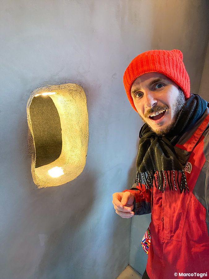 Marco Togni sorridente posa accanto all'apertura nel muro del Kuma no Te Cafe, Osaka.