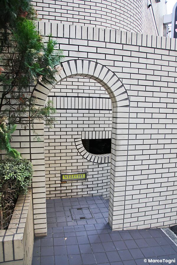 Ingresso arcuato in mattoni bianchi di un love hotel in Giappone.