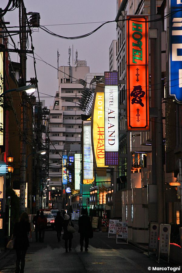 Strada con insegne luminose di love hotel in Giappone di notte.