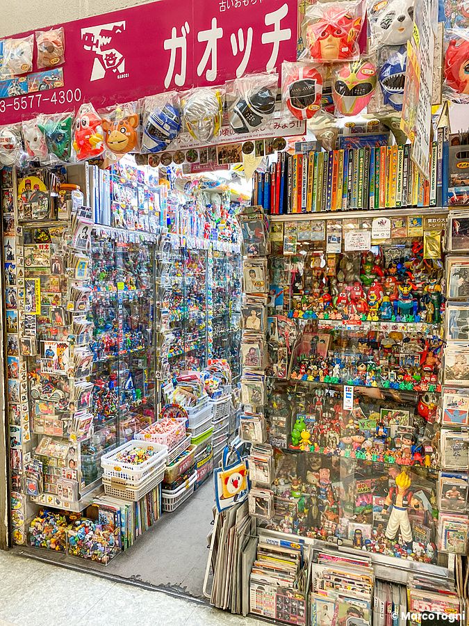 Un negozio Mandarake stracolmo di giocattoli, figure e articoli da collezione esposti su scaffali a tutta altezza.