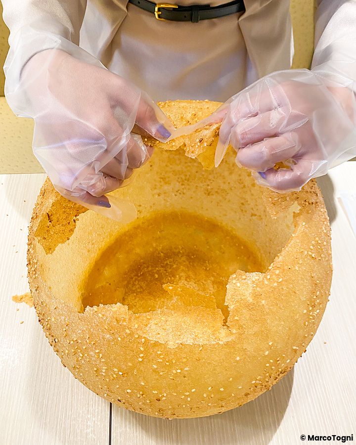 Una palla gigante fritta con sesamo al Mara Daigaku di Ueno viene spezzata da una persona con guanti.