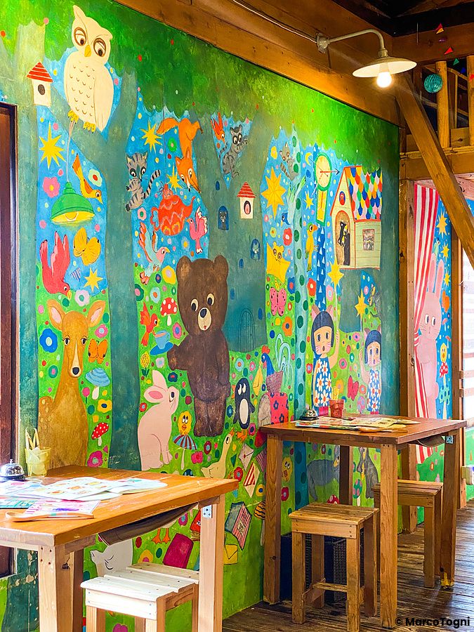 Una parete dipinta con motivi colorati di animali e alberi all'interno del ristorante Hattifnatt di Kichijoji.