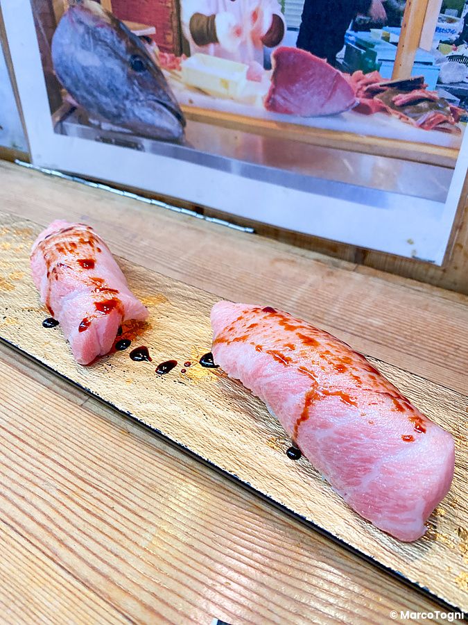 Due pezzi di nigiri di kamatoro su un vassoio dorato all'interno del locale Maguro Koya a Osaka.