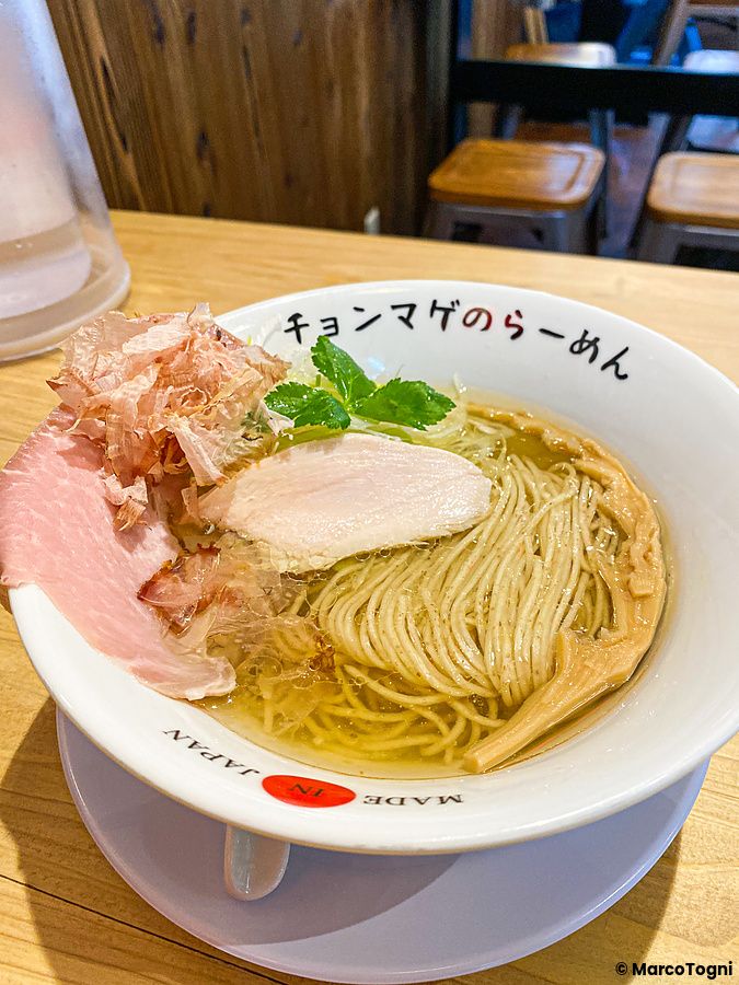 Una ciotola di ramen con brodo chiaro, noodles, carne e scaglie di pesce al Ramen Chonmage Osaka Tenroku Ten ad Osaka.